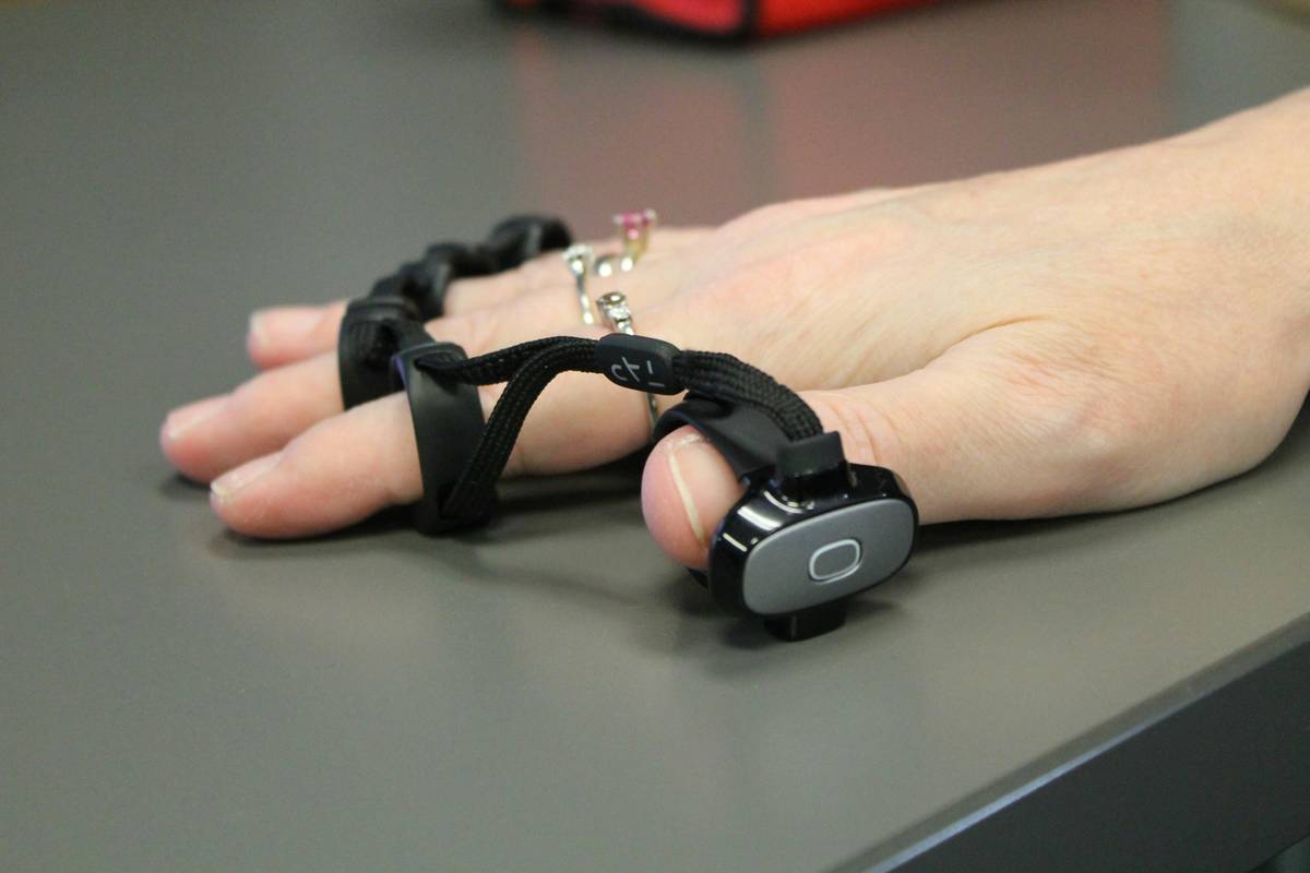 Close-up of hands using assisted-braking belay device with annotated Belay Training Resources guide overlay