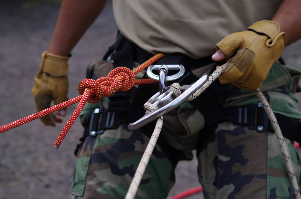 Climber practicing Rope Management Techniques while flaking a rope at a cliffside belay station