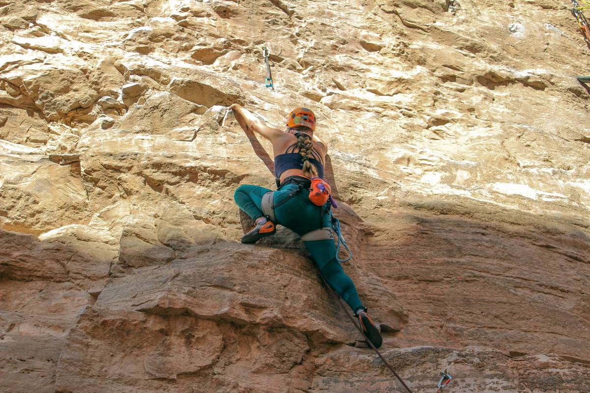Close-up of a climber’s hand gripping a belay device with visible rope tension, illustrating Friction Control Features in action